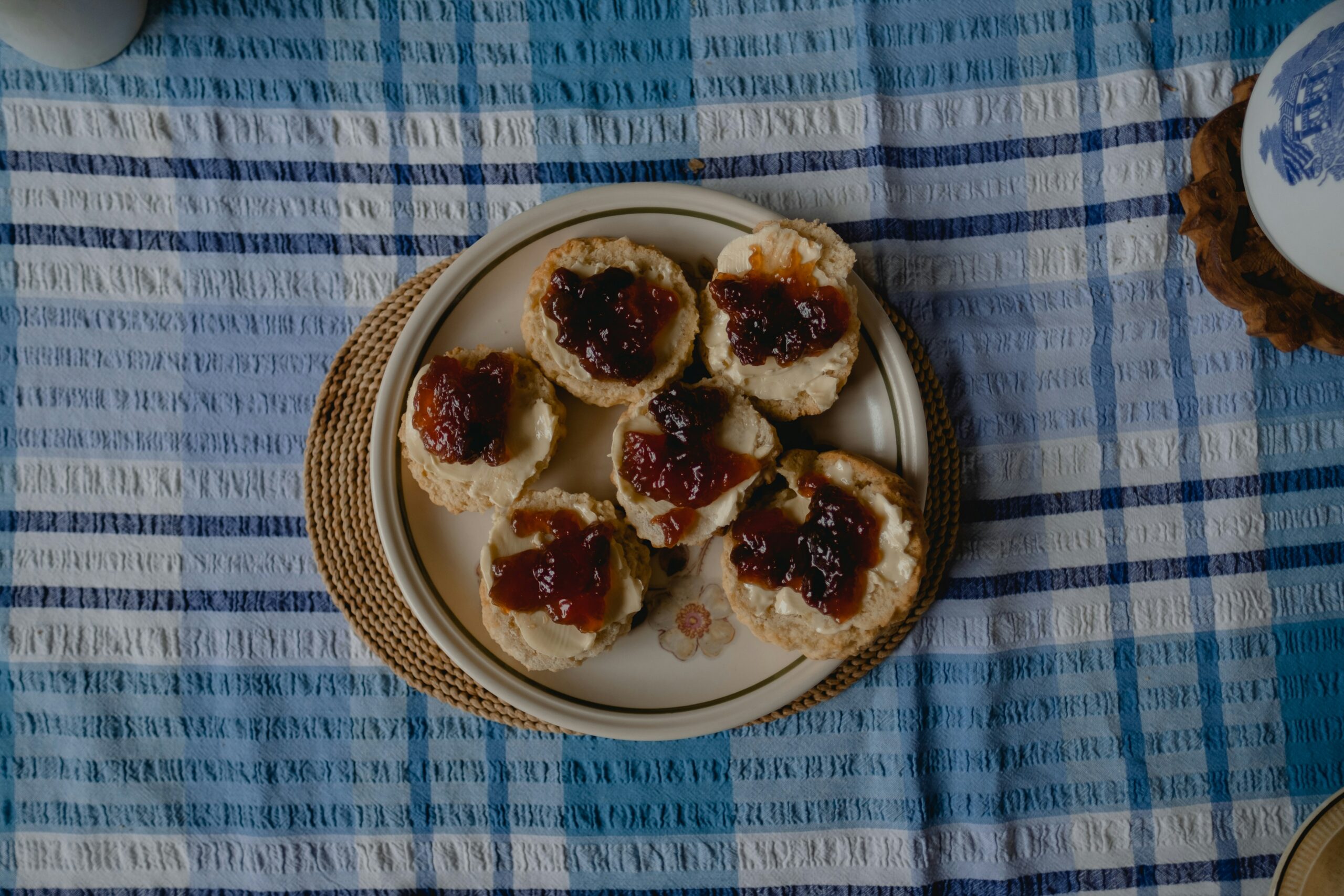 A plate of scones with cream and jam on a table with blue tablecloth