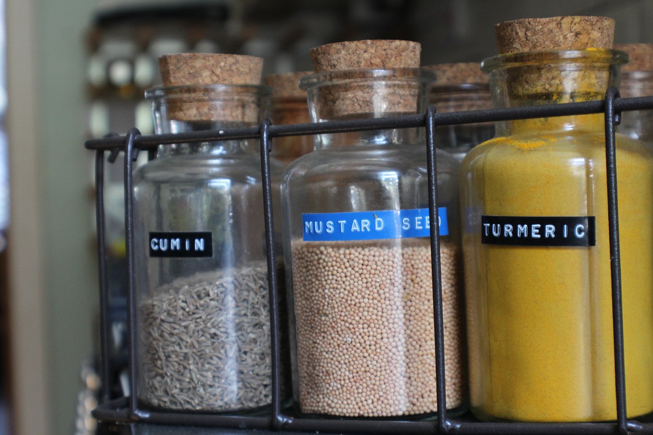 A spice rack of glass bottles with cumin, mustard seed and turmeric