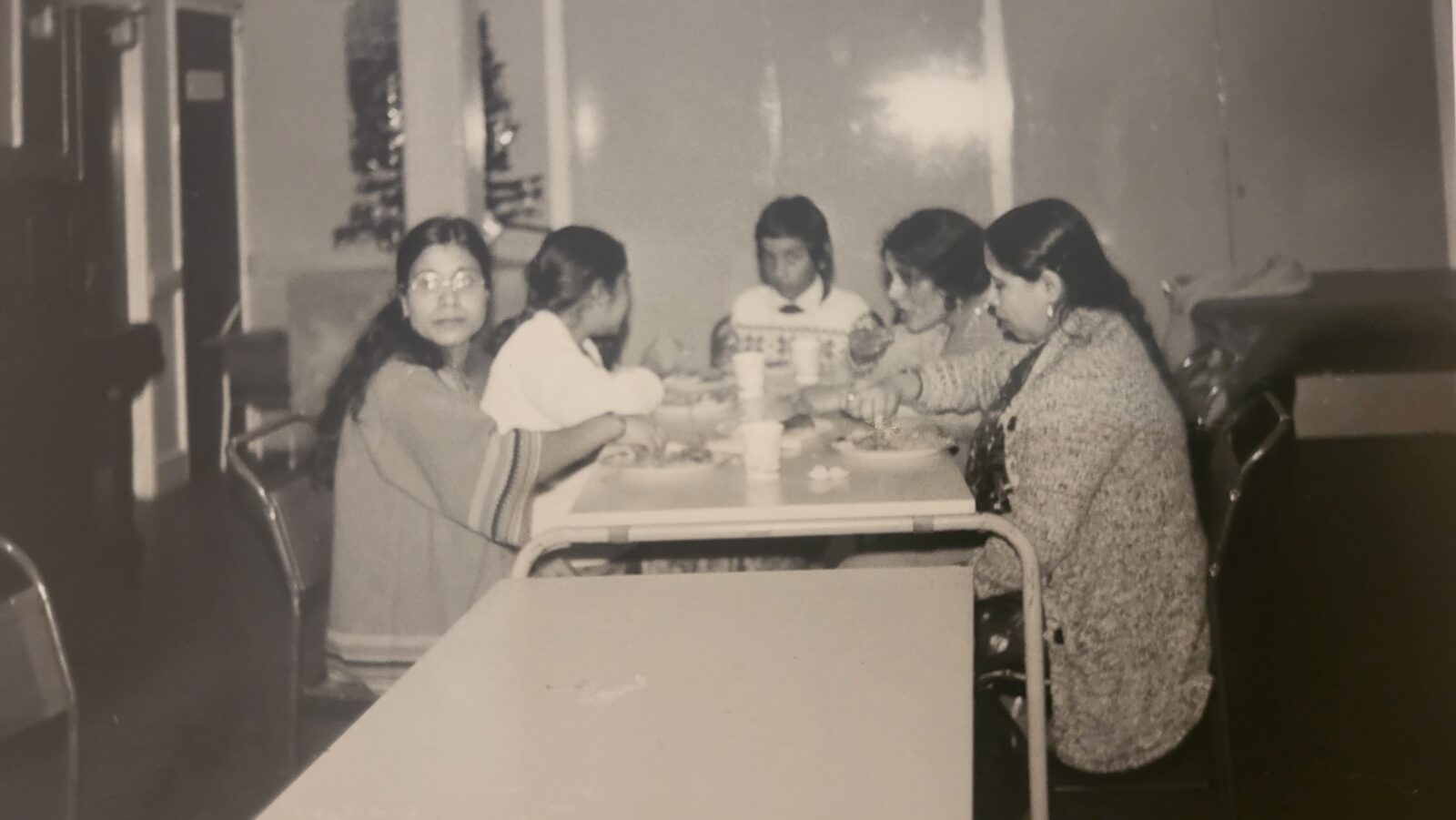 A group of women sat at a table making food.